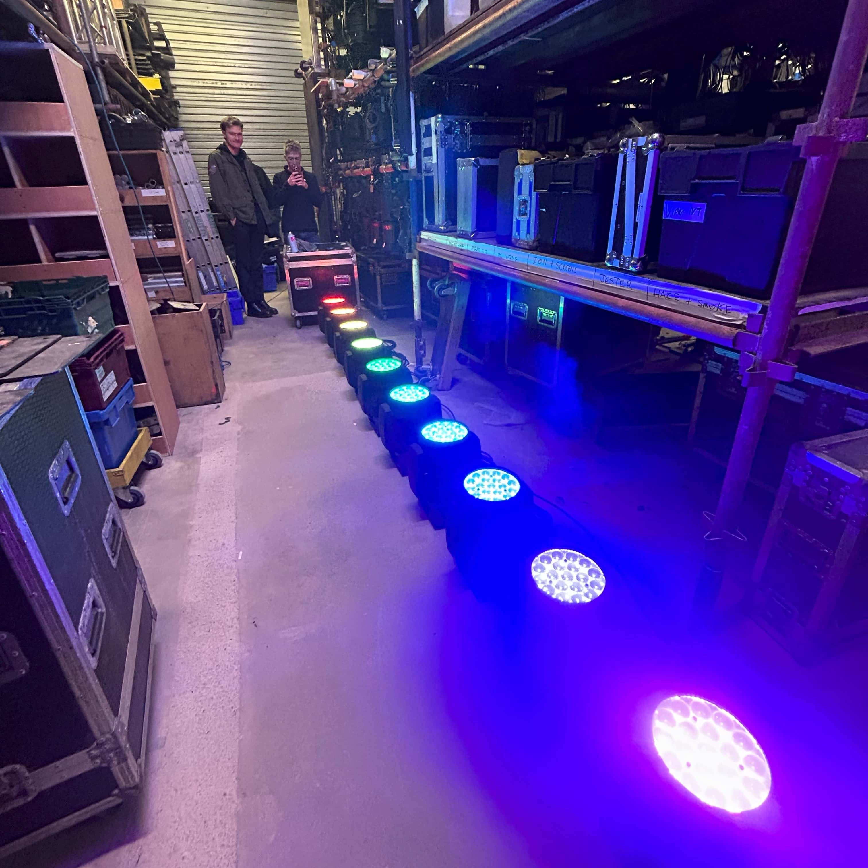 A line of movers set up on the floor lit in rainbow colours